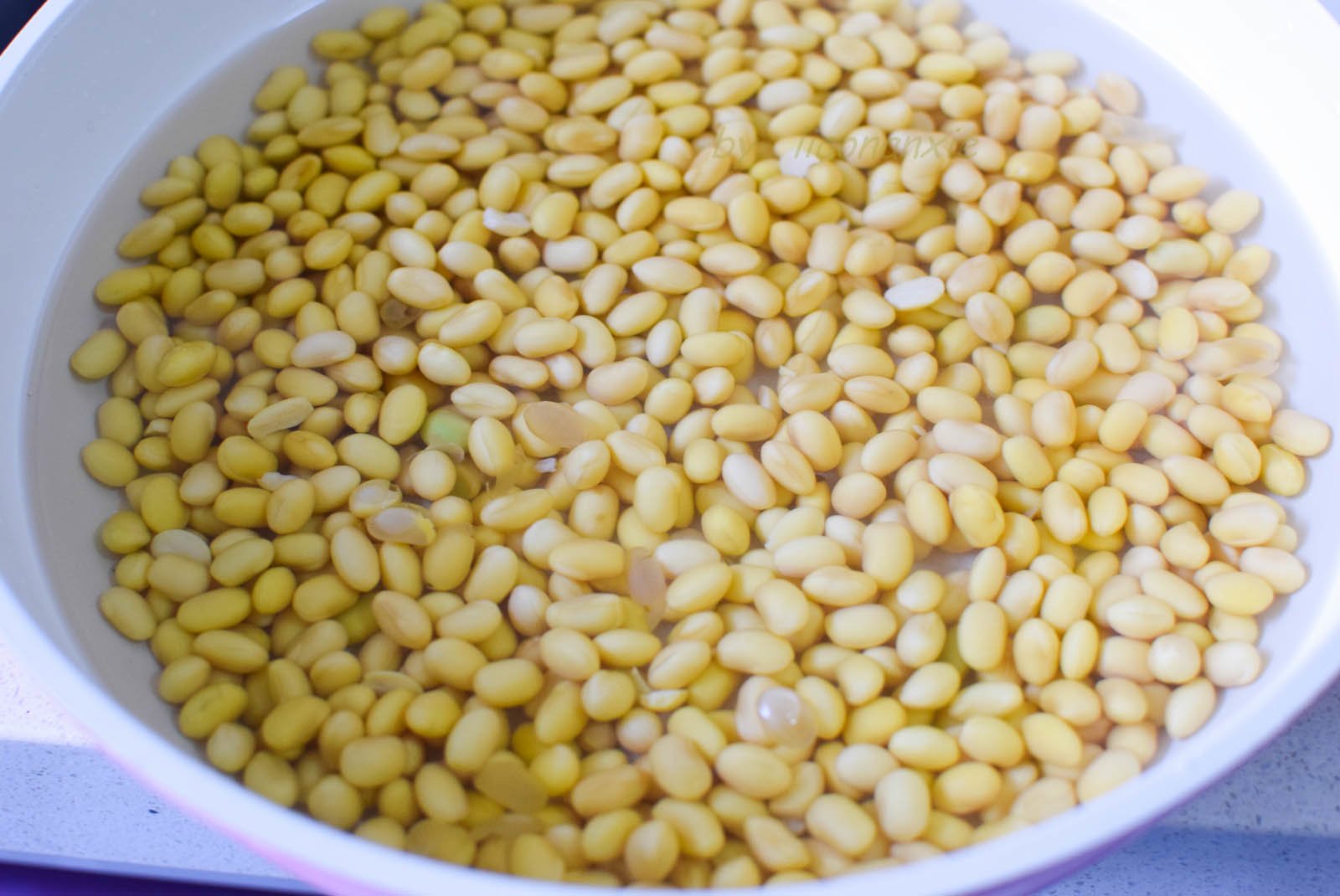 400g đậu nành ngâm trong nước sạch cho nở căng hạt. Mùa lạnh cần ngâm 10 tiếng trở lên, mùa nóng thì nên thay nước thường xuyên để tránh bị chua.