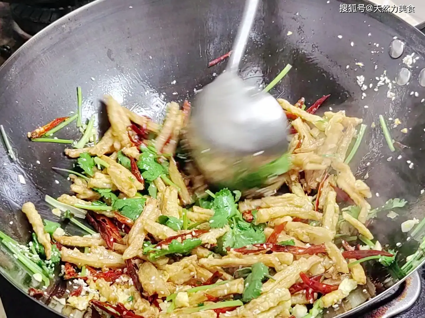 Phi thơm tỏi, gừng, cho ớt khô vào đảo nhanh tay, rồi trút củ sen chiên vào xào.